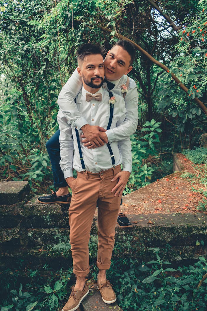 A joyful couple embraces in a lush, summer forest setting, celebrating love and togetherness.